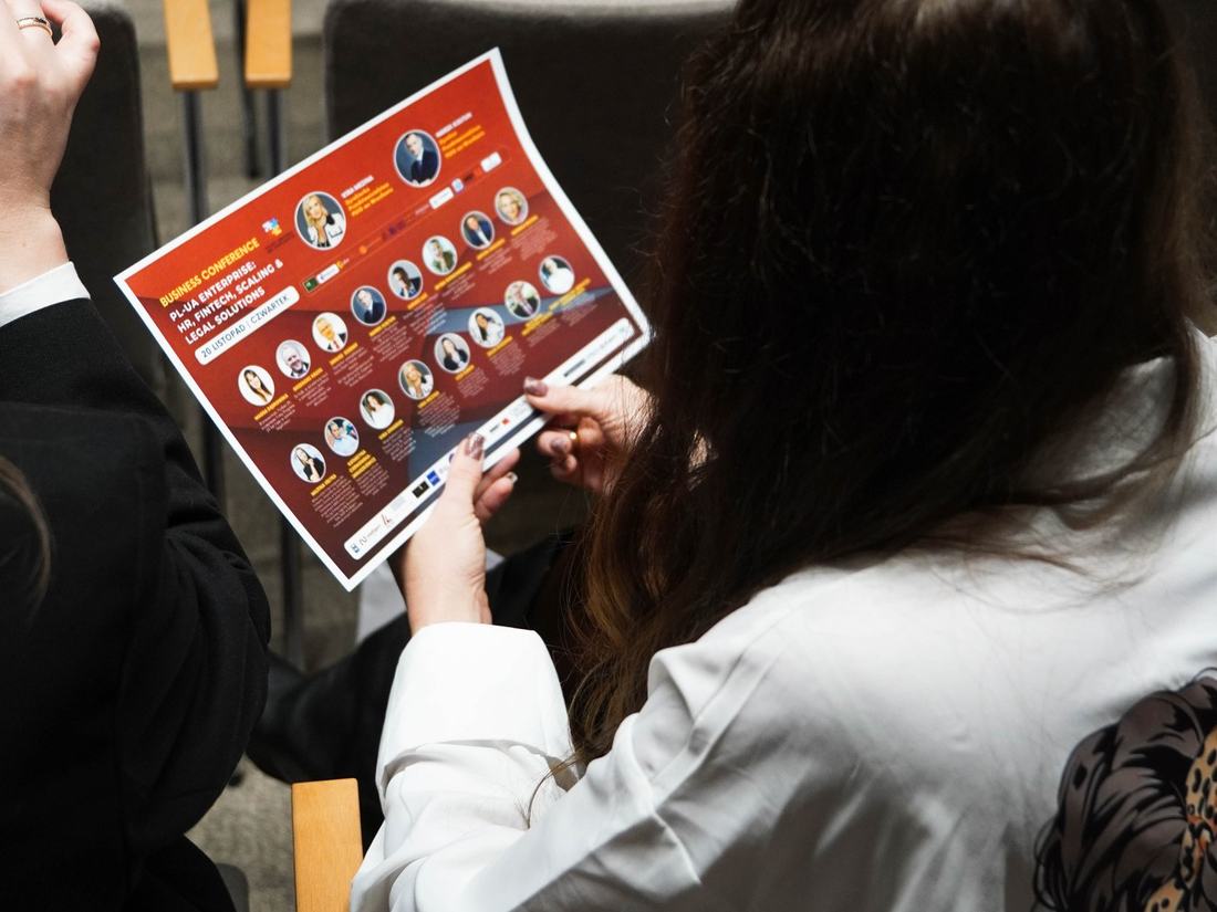 Uczestniczka konferencji przegląda drukowany program z sylwetkami prelegentów